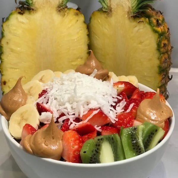 A bb Acai & Juice Store acai bowl with strawberries, kiwi, bananas, peanut butter, and coconut flakes.