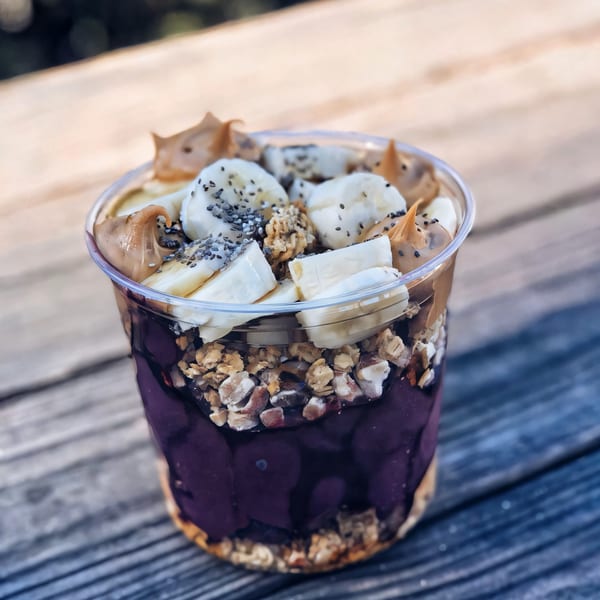A bb Acai & Juice Store acai bowl with bananas, peanut butter, chia seeds, and granola.